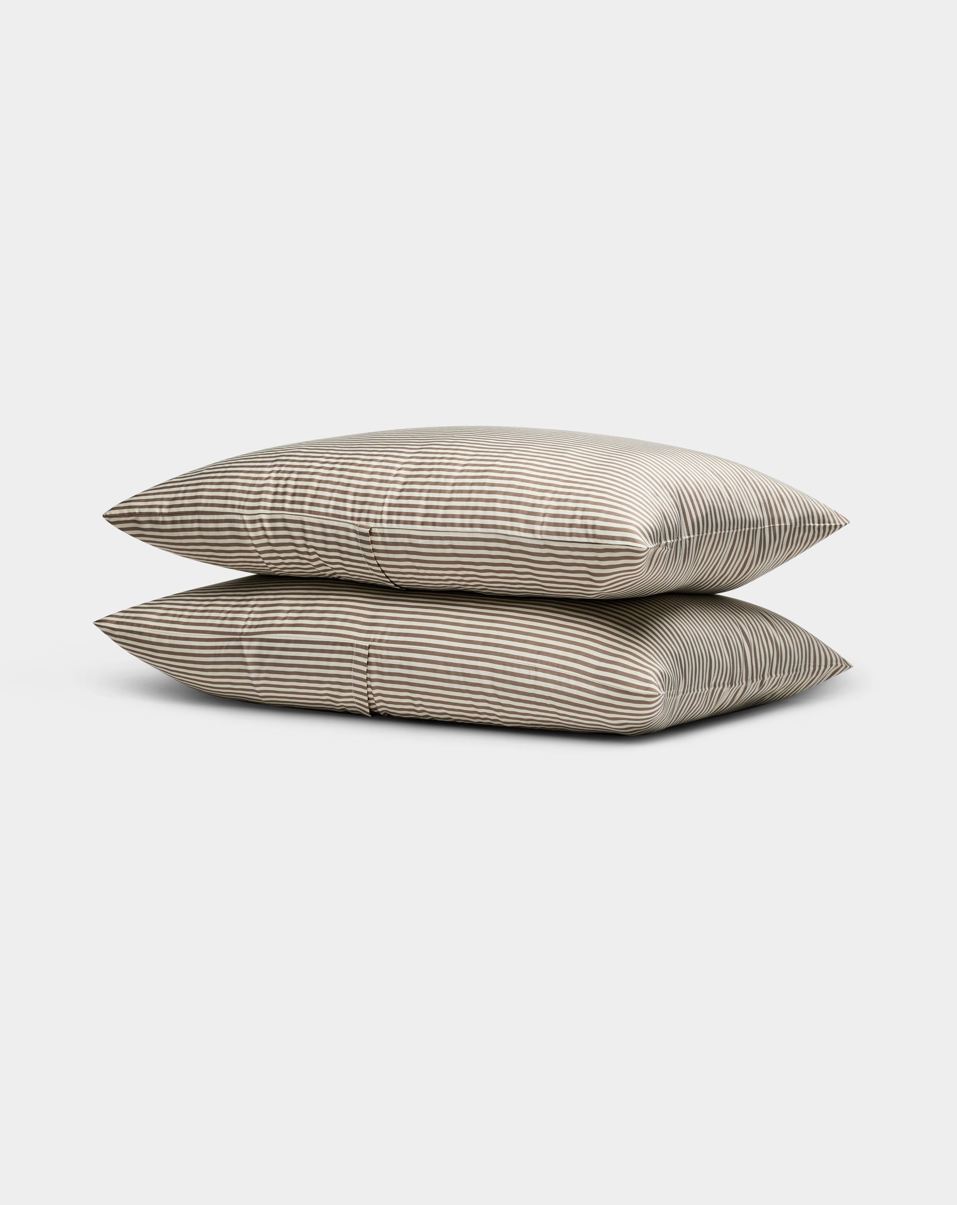 Two Cozy Earth Bamboo Pillowcases in beige, featuring thin horizontal white stripes, are stacked neatly against a plain light gray background.|Color:Classic Stripe in Ebony