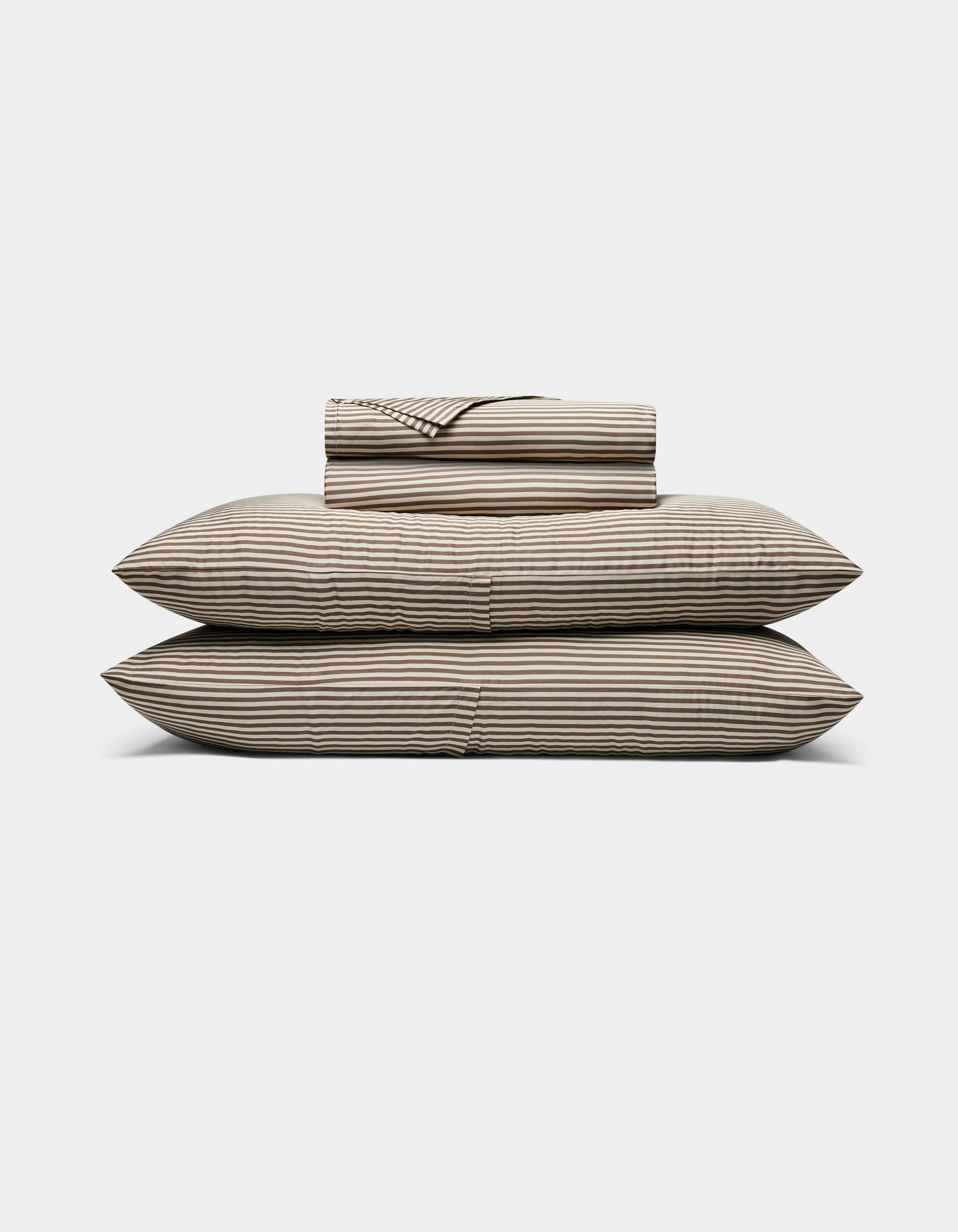 The Cozy Earth Bamboo Sheet Set, featuring striped beige and black sheets and pillowcases, is neatly stacked on two large pillows against a plain white background.|Color:Classic Stripe in Ebony