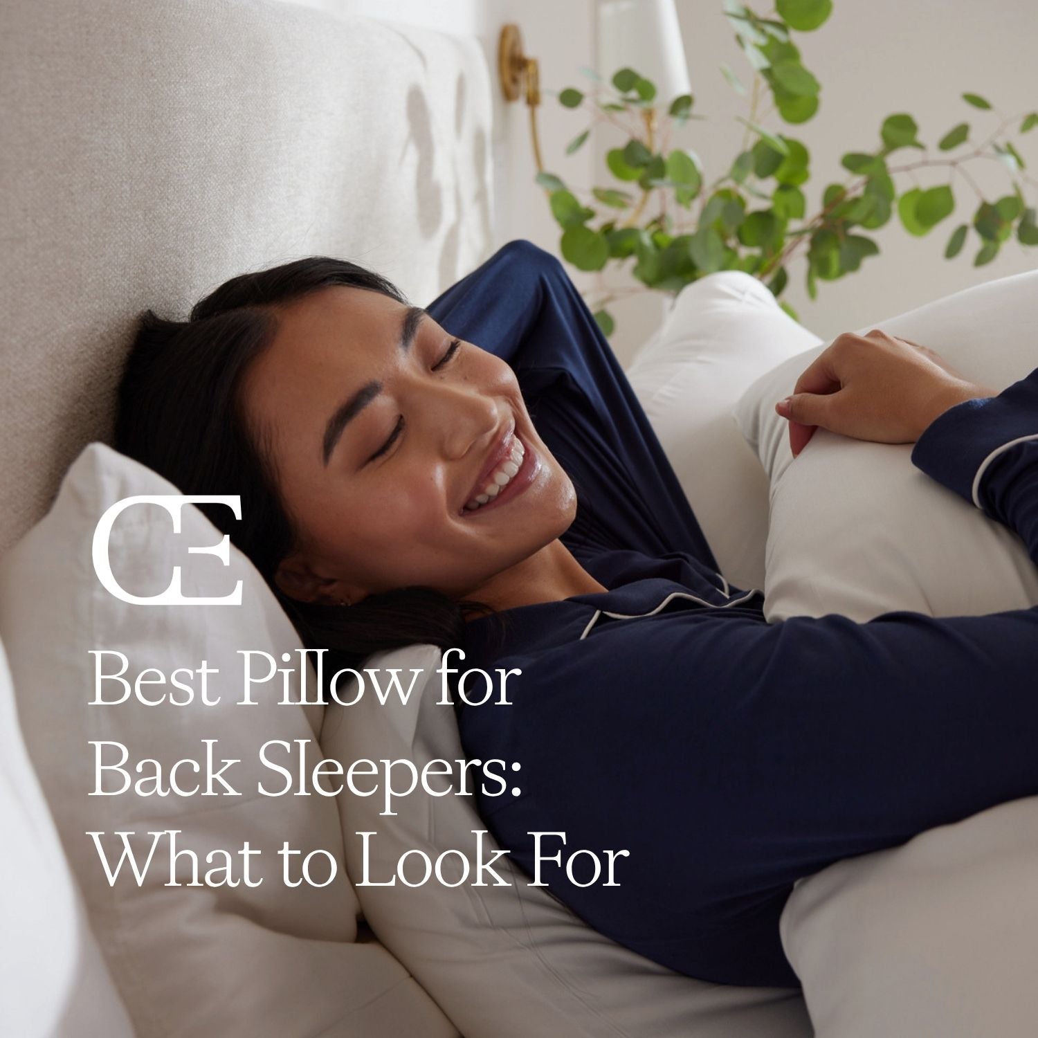 A woman lies against pillows on a bed