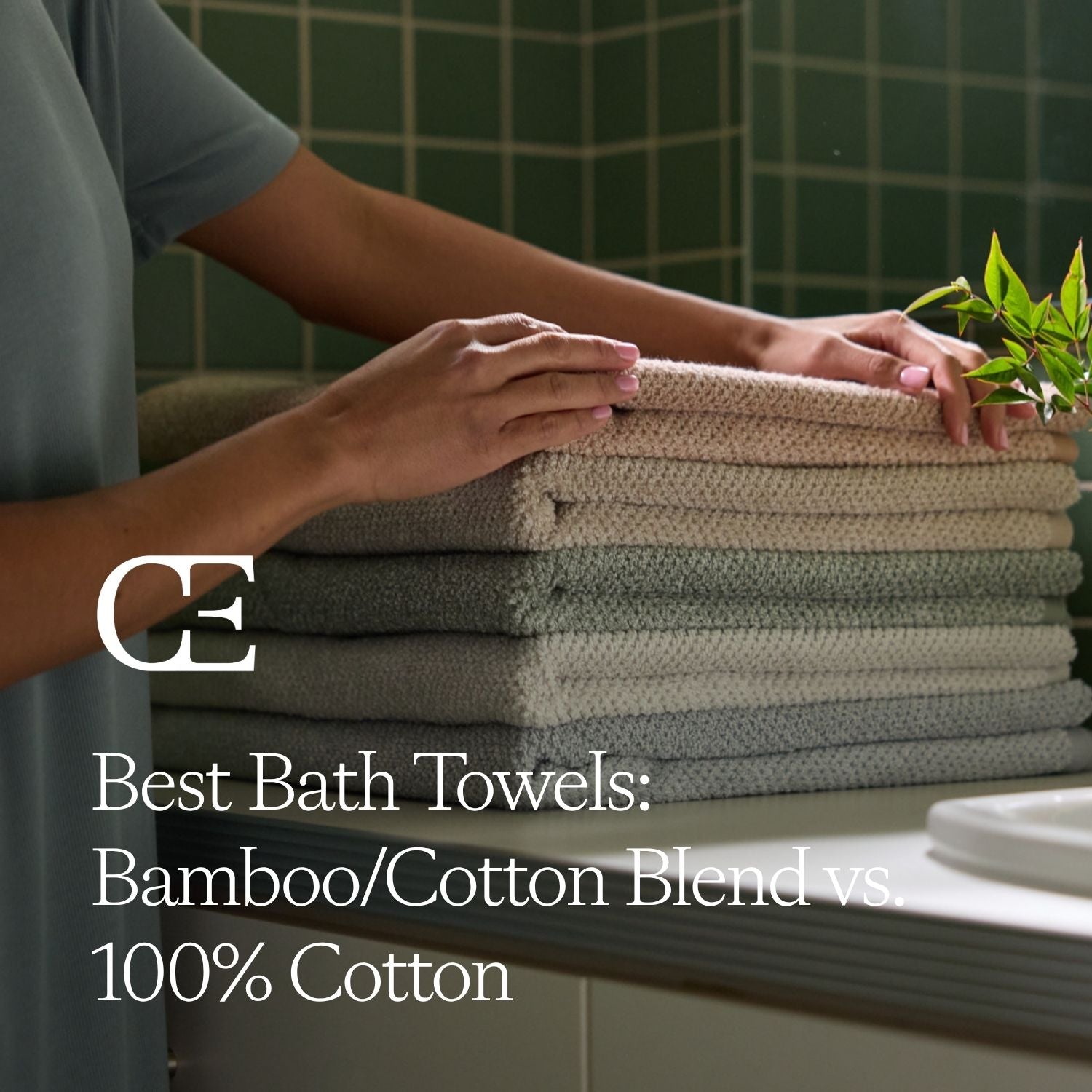 a person rests a stack of bath towels on a bathroom countertop