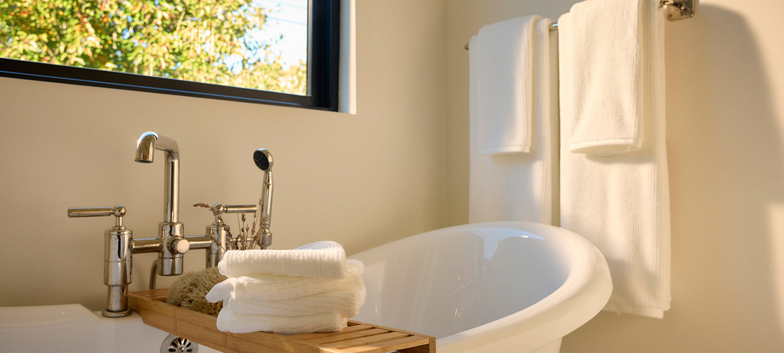Four white towels hang next to a bathtub