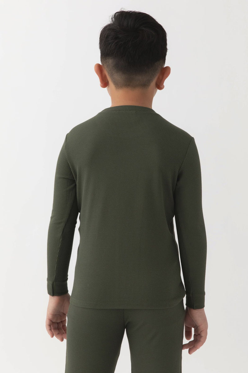 A young boy with short dark hair, seen from behind, wears the Cozy Earth Children's Bamboo Waffle Knit Base Layer Long Sleeve in olive green. The background is plain white.