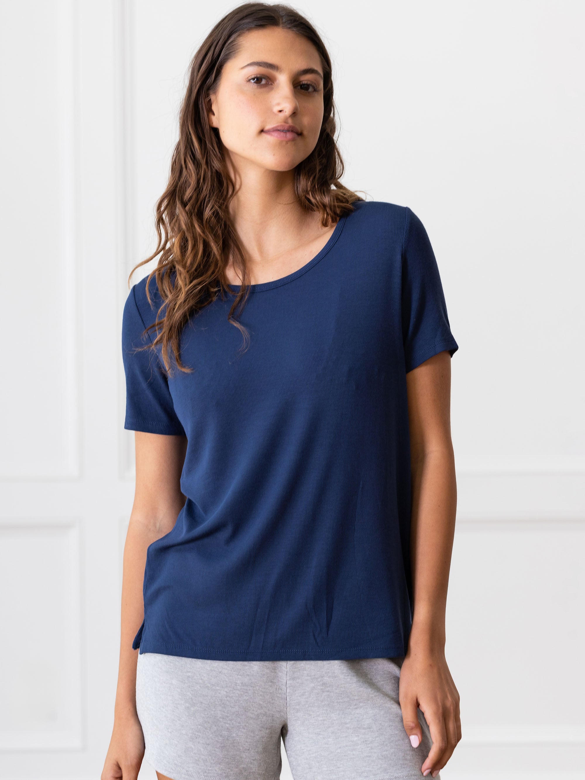 Woman wearing a blue Cozy Earth Rib Knit Short Sleeve Lounge Top and gray shorts against a white background 