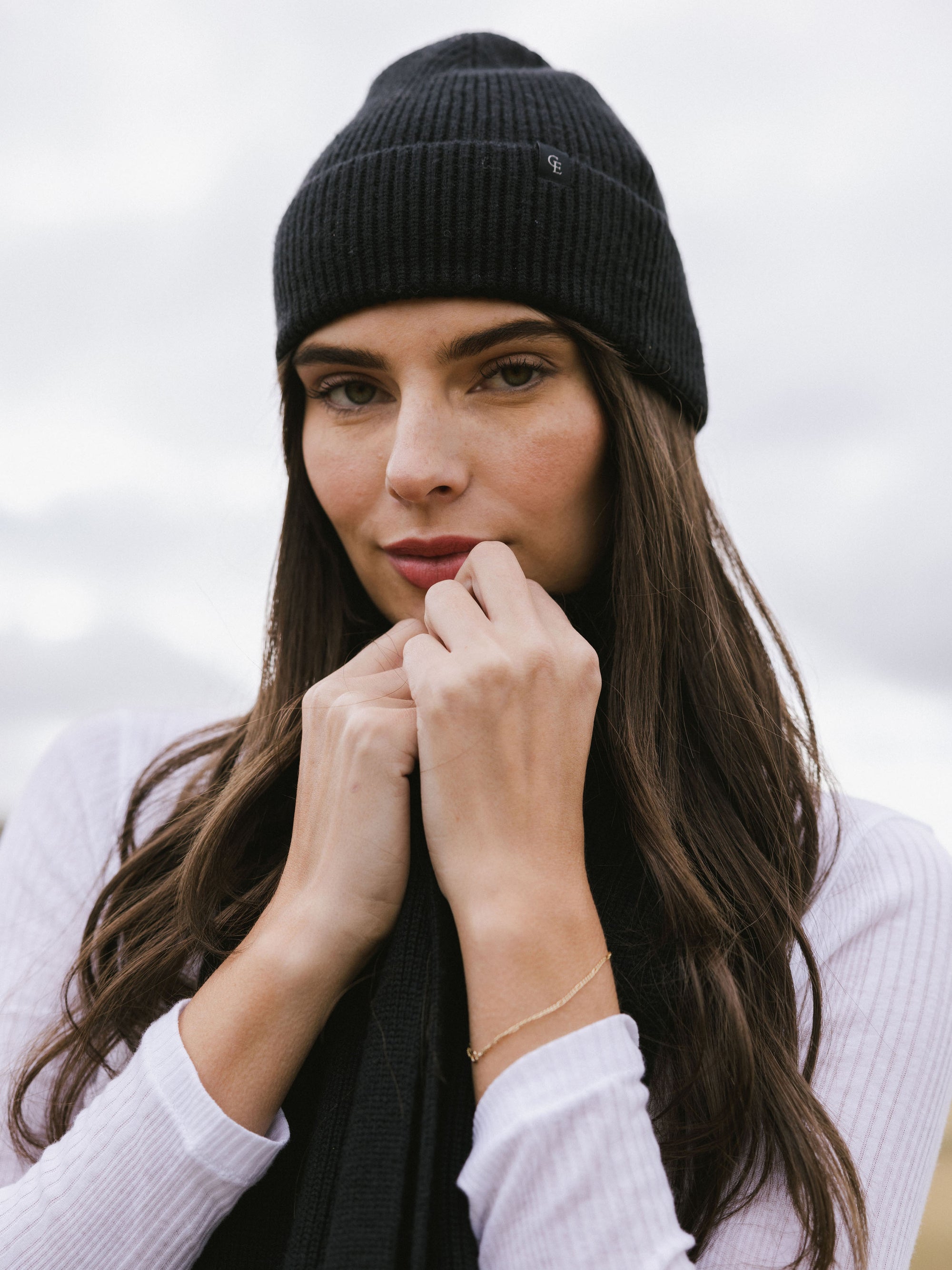 Woman wearing a black knit beanie and scarf on a white background 
