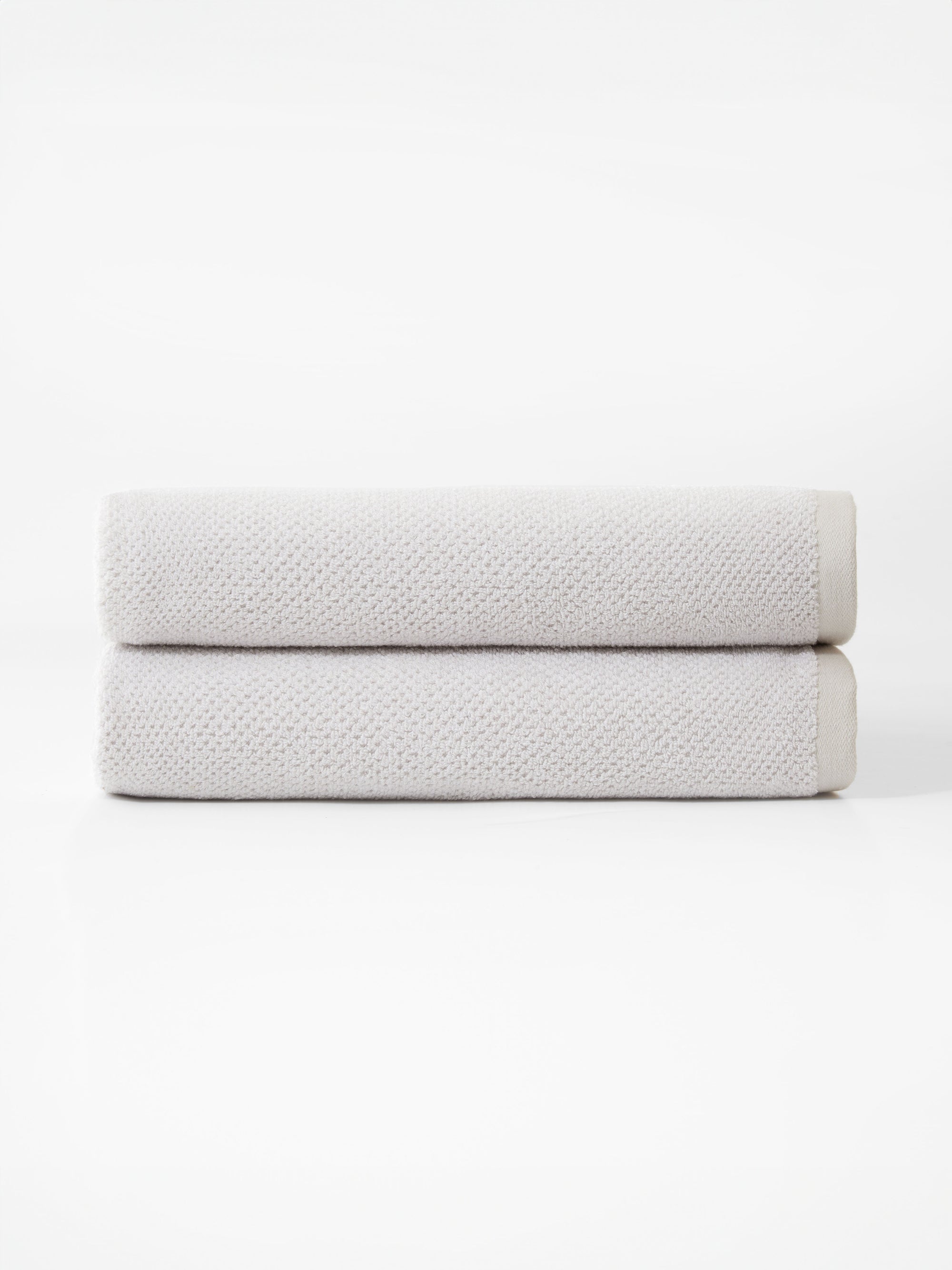Cozy Earth’s Nantucket Bath Towel Set features two neatly folded, light gray towels stacked together against a plain white background.