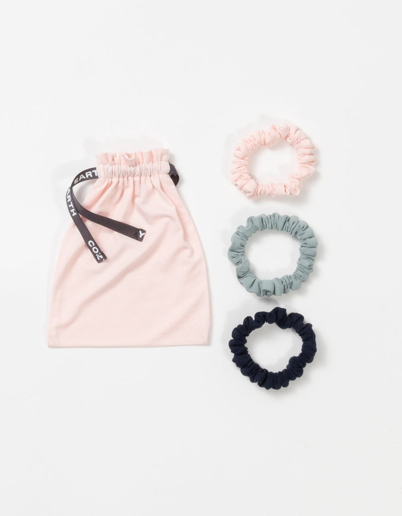 Cozy Earth Bamboo Stretch Knit Skinny Scrunchies in Navy, Brook, and Blossom pictured with storage bag on a white background.