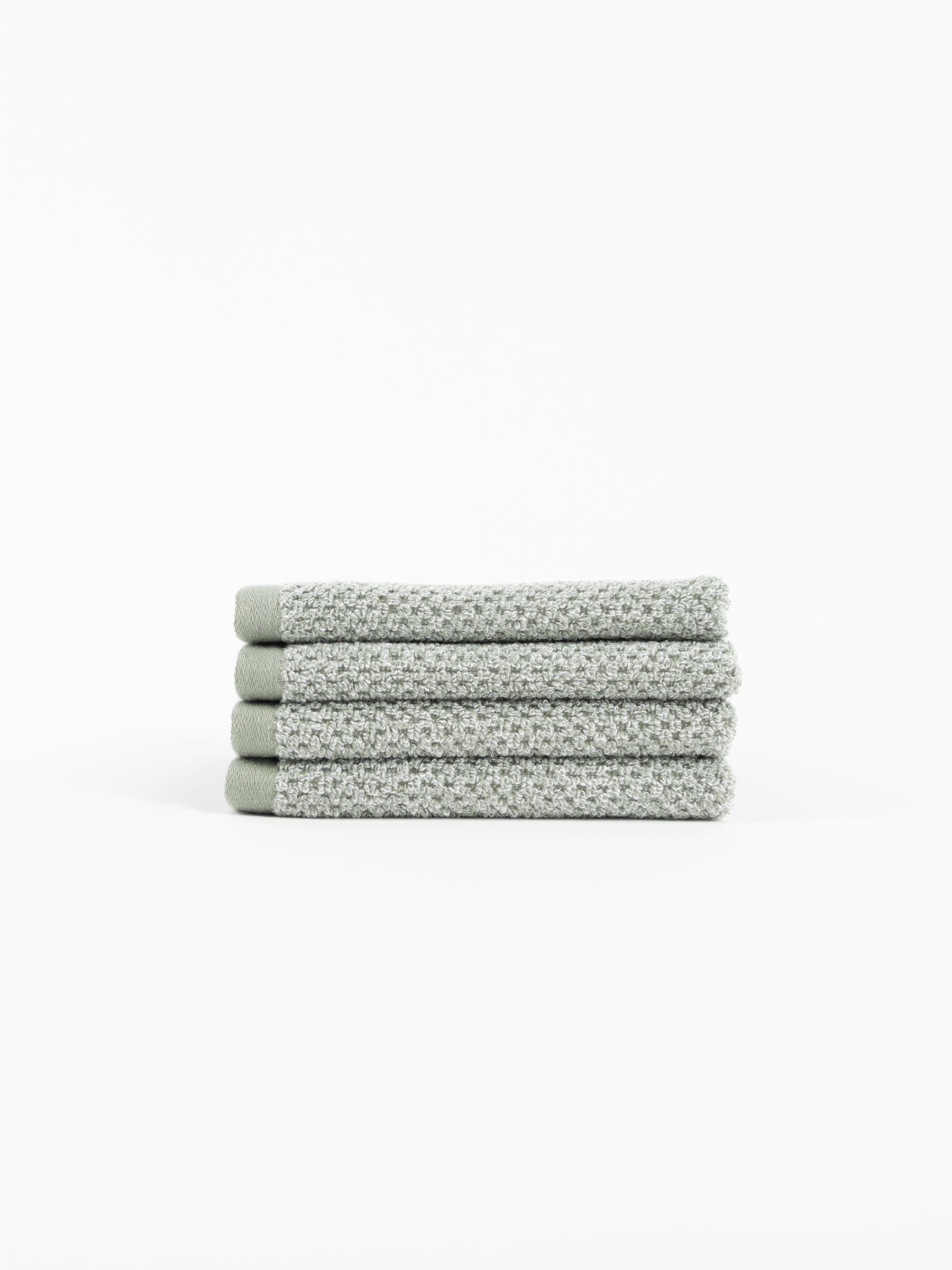 A neatly folded stack of four Cozy Earth Nantucket Bath Towels in textured light gray rests on a white background.