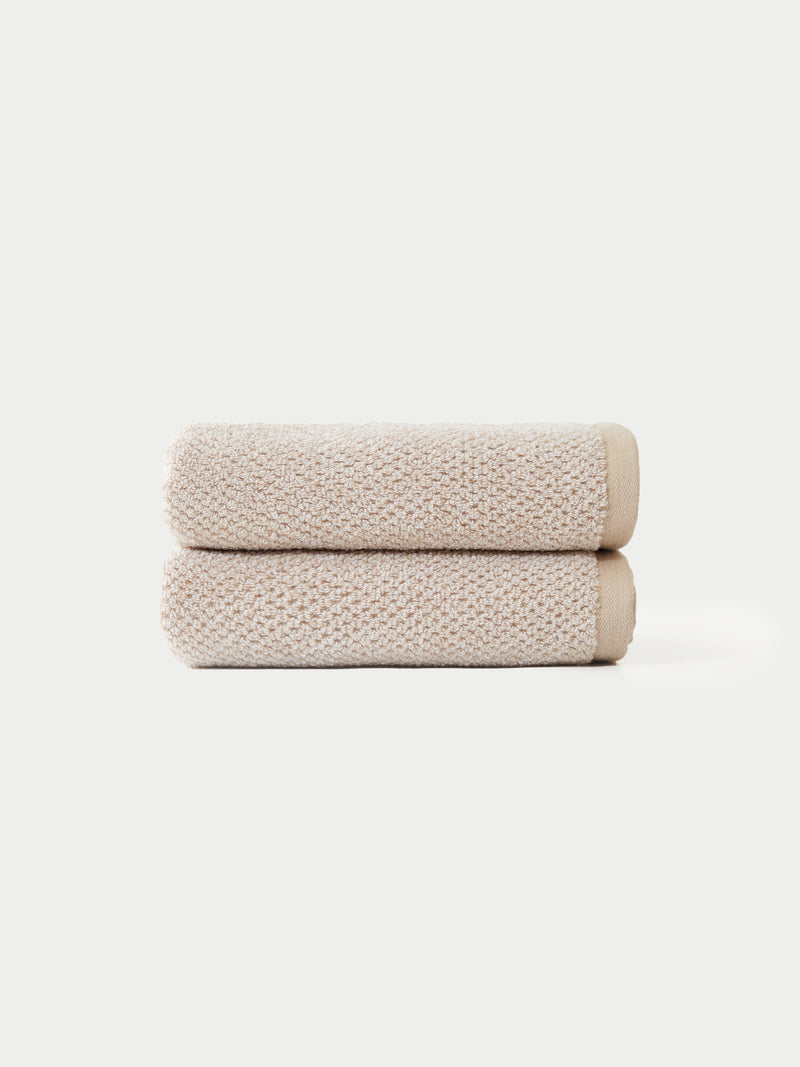 Two Nantucket Bath Towels by Cozy Earth, neatly folded and stacked atop each other, are displayed against a plain white background.