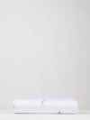 A neatly folded Bamboo Duvet Cover from Cozy Earth is laid flat against a plain, light gray background. The cover is predominantly white with small, colorful illustrations or designs scattered across its surface. |Color:Skiers