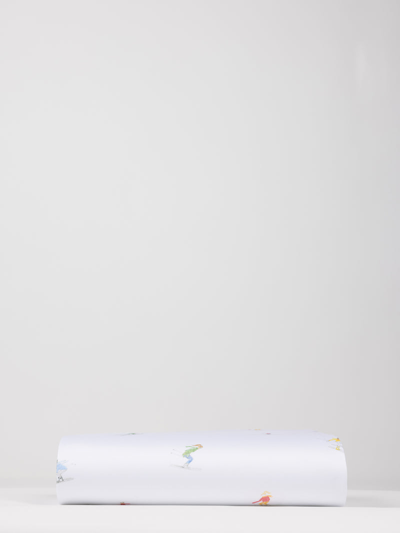 A neatly folded Bamboo Duvet Cover from Cozy Earth is laid flat against a plain, light gray background. The cover is predominantly white with small, colorful illustrations or designs scattered across its surface.