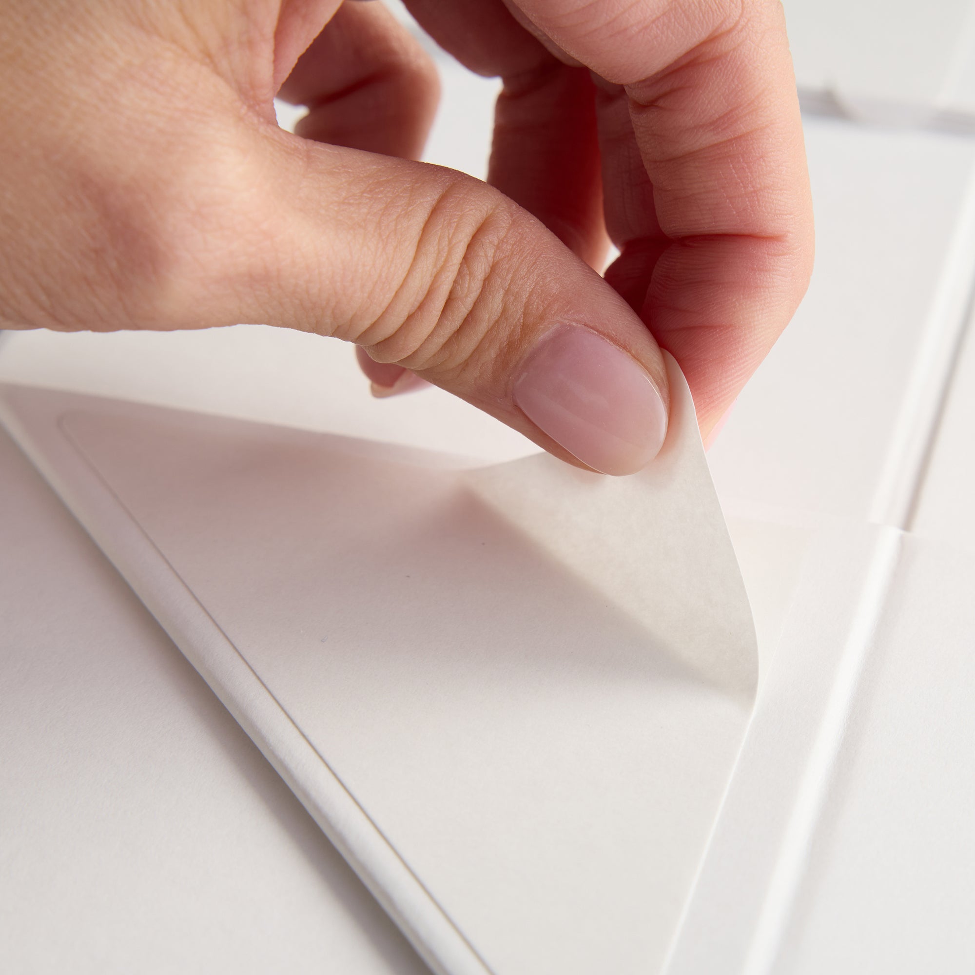 Hand pulling adhesive strip on gift box 