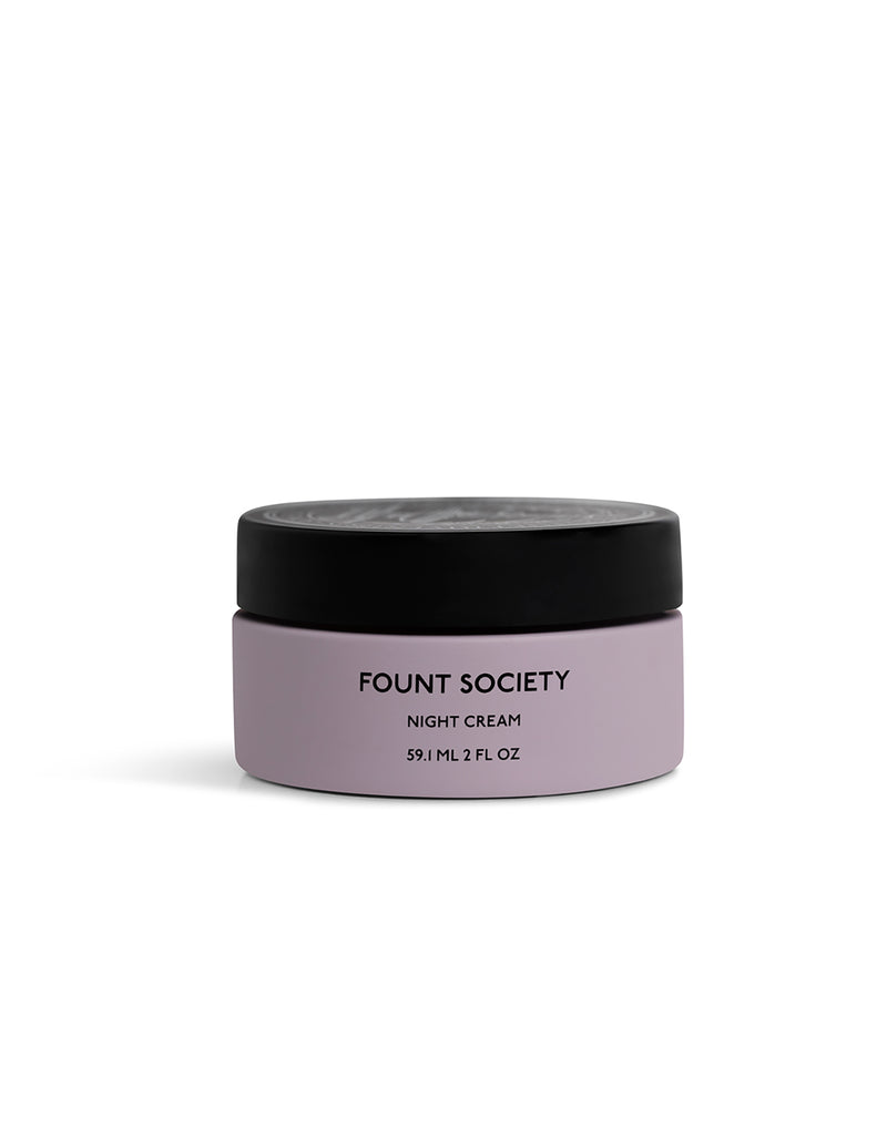 A small, round jar of Cozy Earth Day-to-Night Essentials cream with a black lid and light purple container, labeled with product details in black text.