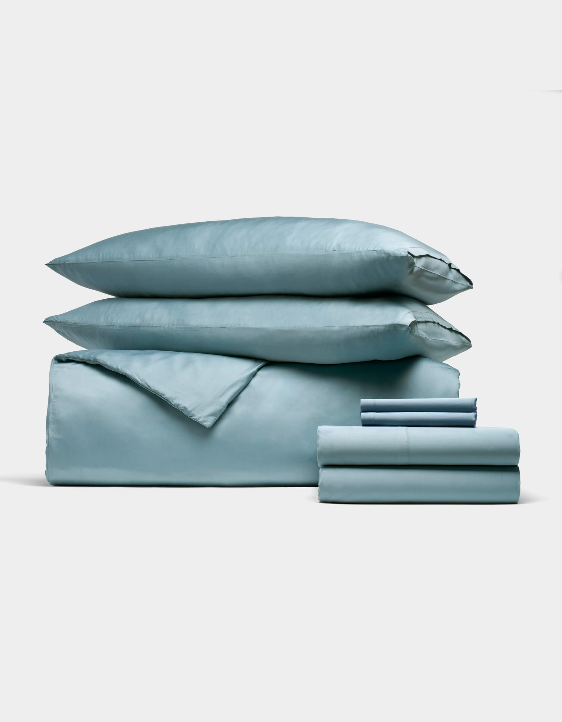 The Cozy Earth Bamboo Bedding Ultimate Bundle, featuring a light blue duvet cover, two pillows, and neatly folded sheets, is displayed against a white background.