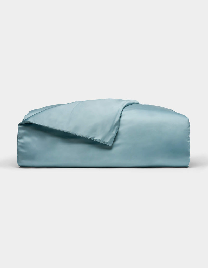 A neatly folded Cozy Earth Bamboo Duvet Cover in light blue, with one corner draped over the top, displayed against a plain white background.