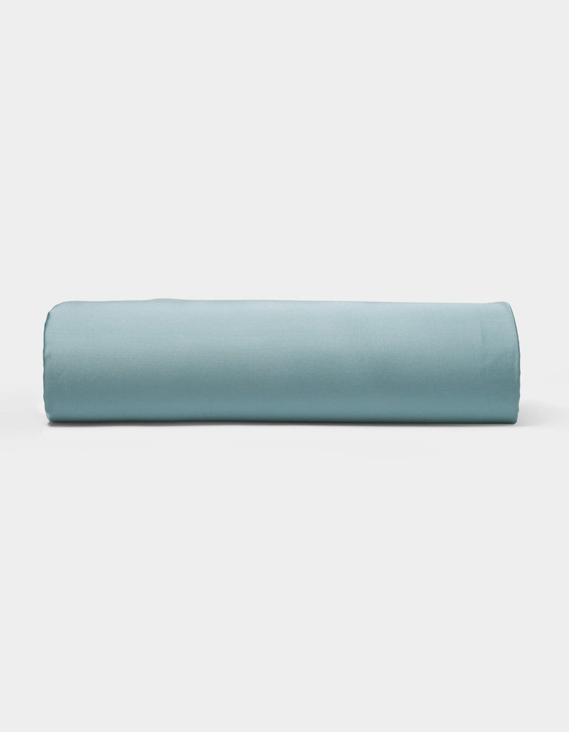 A neatly rolled light blue Bamboo Fitted Sheet by Cozy Earth is displayed against a plain white background.