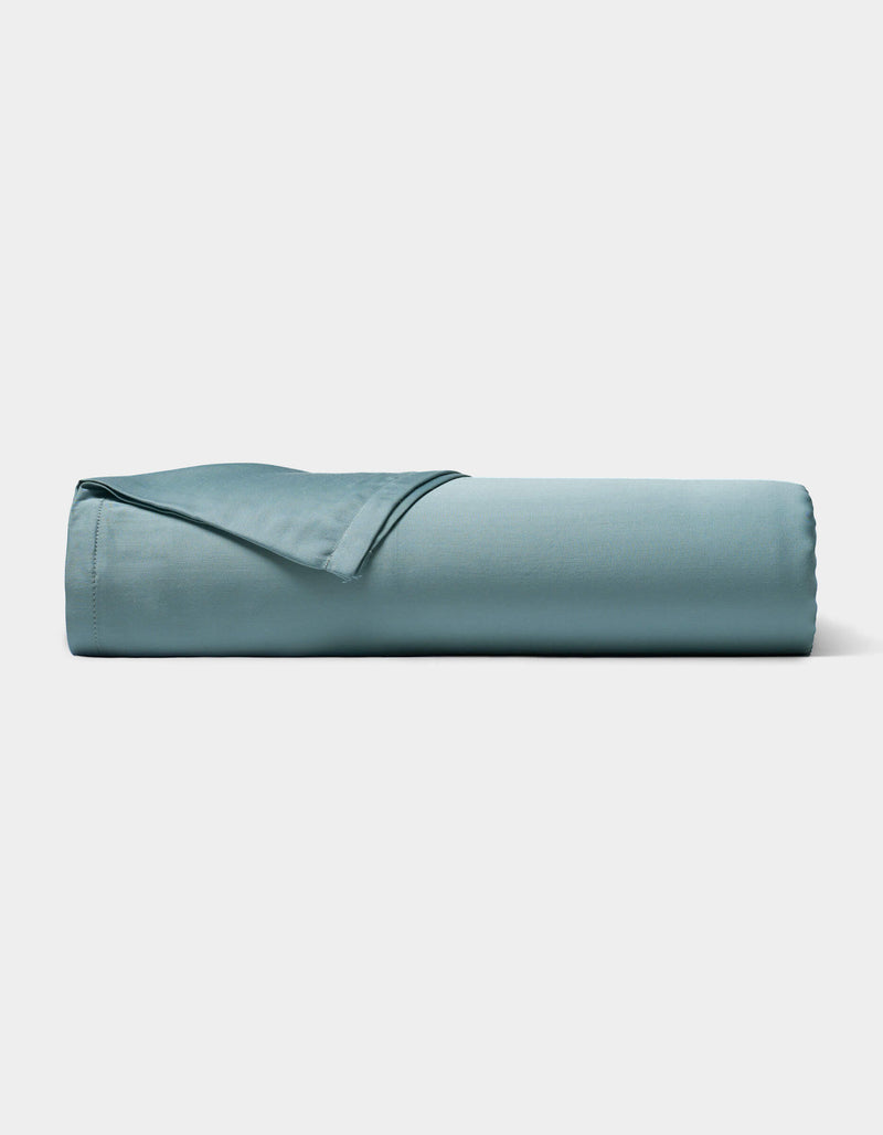 A neatly rolled Bamboo Sheet Set by Cozy Earth in light blue is displayed on a plain white background.