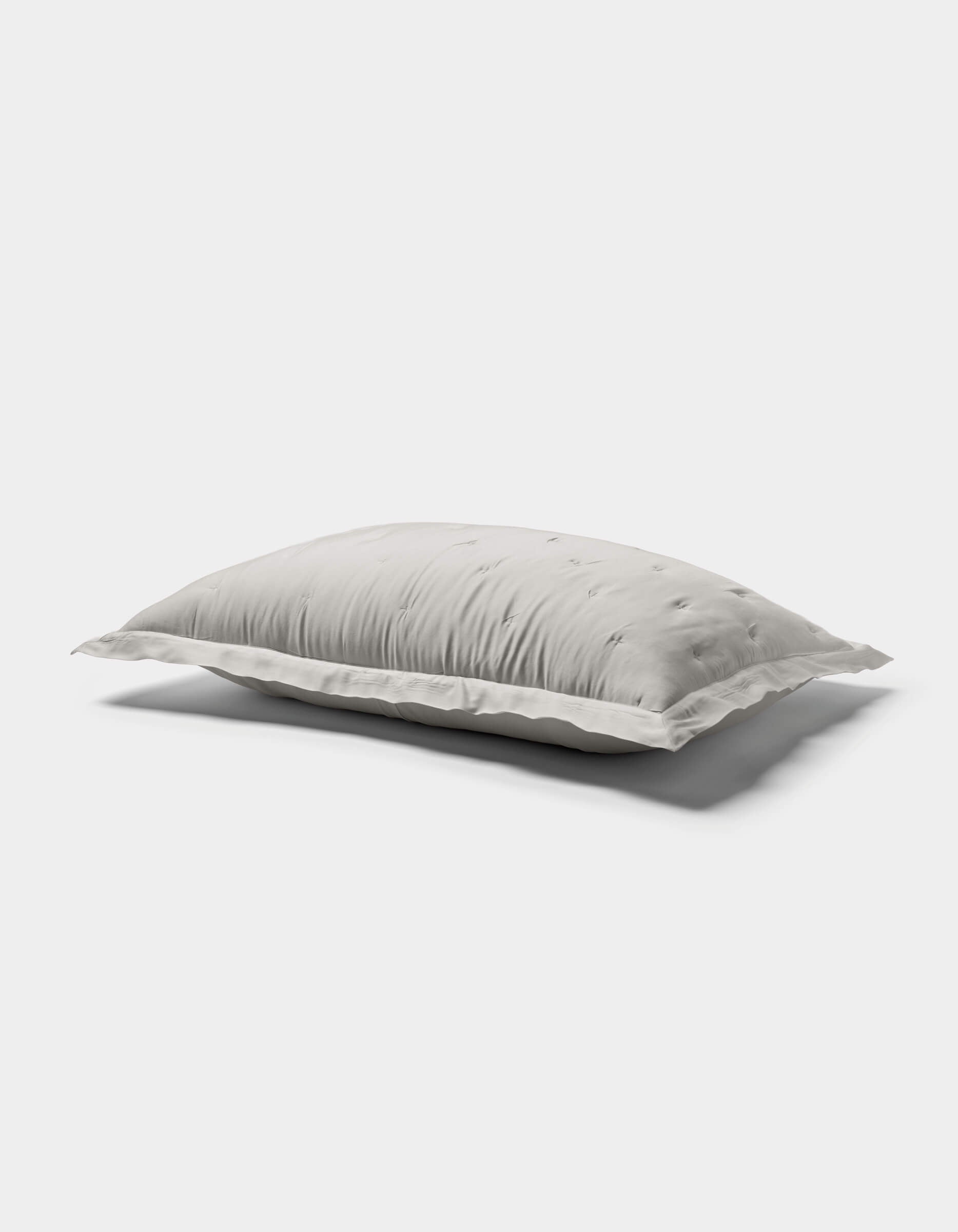 A white, rectangular Bamboo Quilted Sham by Cozy Earth with a soft, fluffy texture rests on a plain light gray background, casting a gentle shadow beneath it.