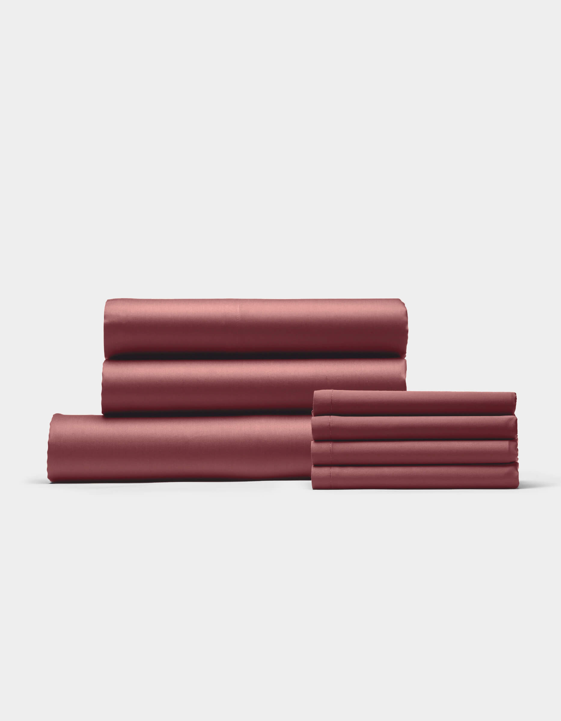 The Cozy Earth Bamboo Bedding Core Bundle, featuring four folded reddish-brown bed sheets and two matching pillowcases, is neatly stacked against a plain white background.|Color:Mulberry