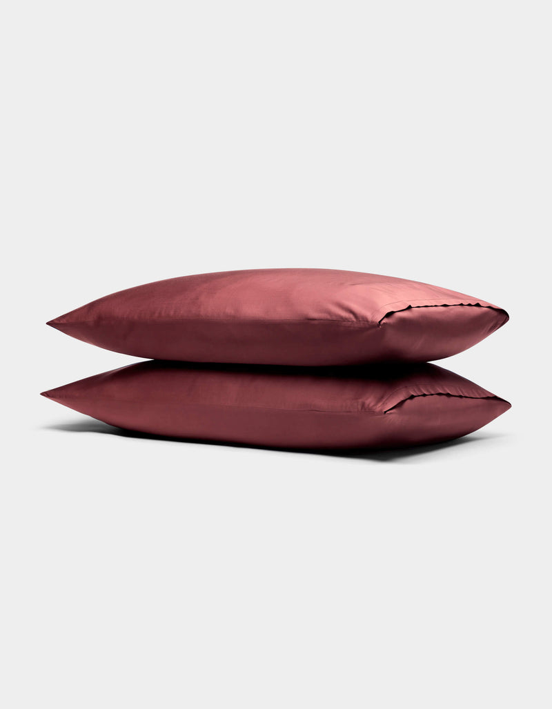 Two stacked, smooth, rose-colored Cozy Earth Bamboo Pillowcases are displayed on a neutral light gray background.