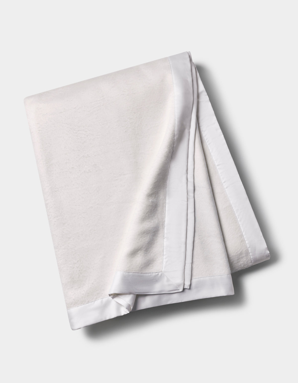 The Cozy Earth Bamboo Blanket, featuring a smooth satin border, is shown folded on a light gray background. |Color:White