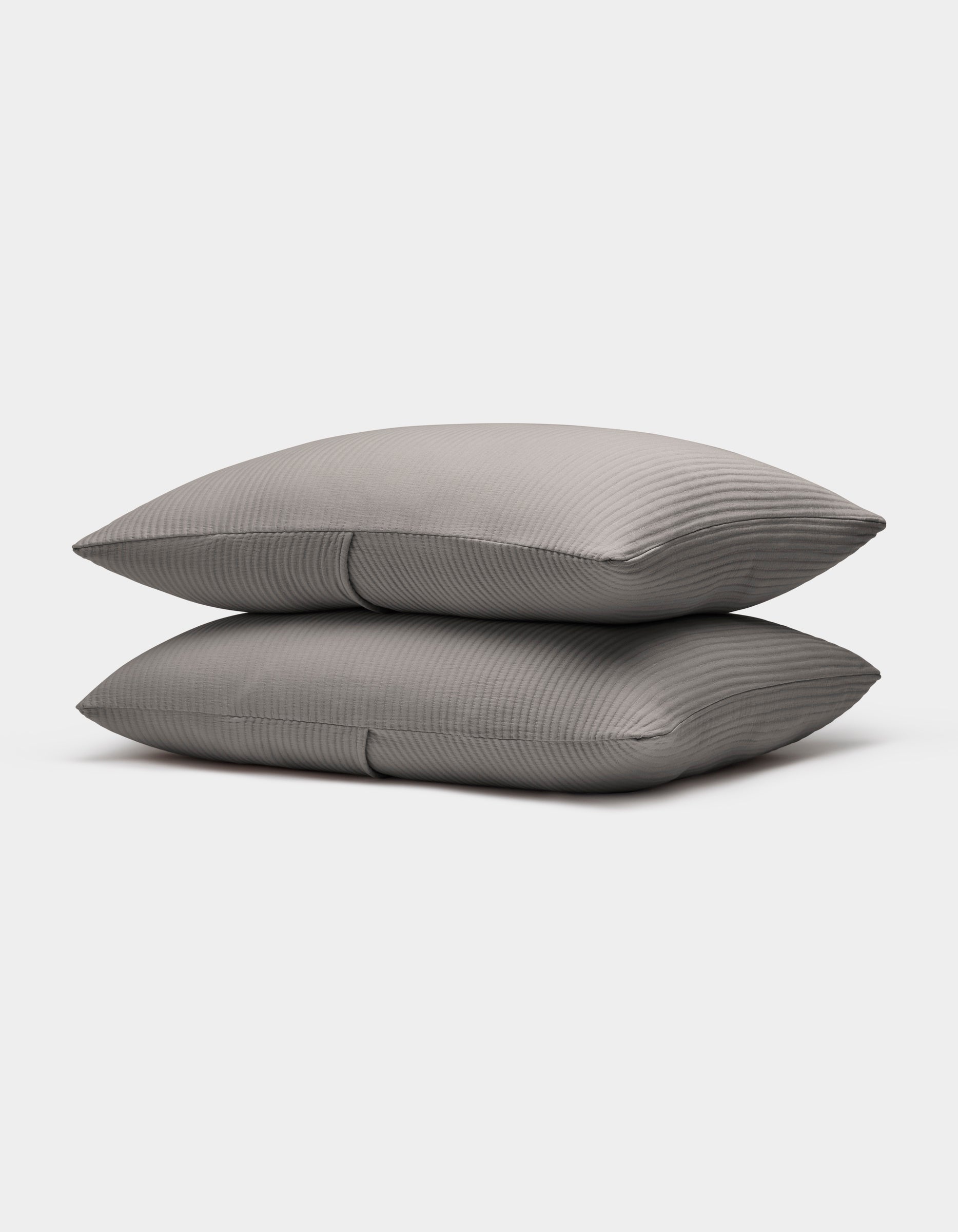 Two neatly stacked Bamboo Coverlet Shams by Cozy Earth in gray with stripes, displayed on a plain white background.|Color:Charcoal