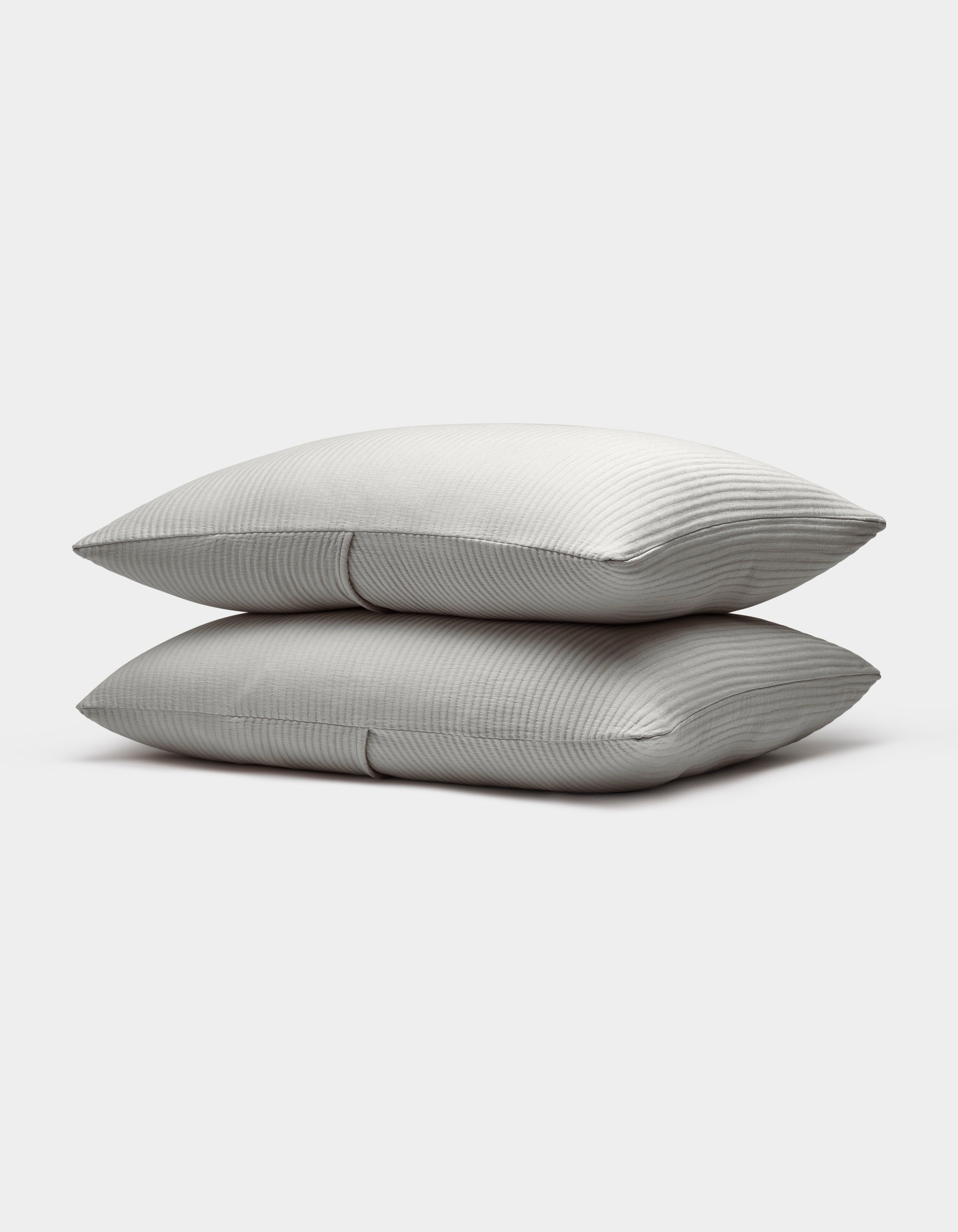 Two neatly stacked Bamboo Coverlet Shams by Cozy Earth, light gray with a subtle striped pattern, are displayed on a plain white background.