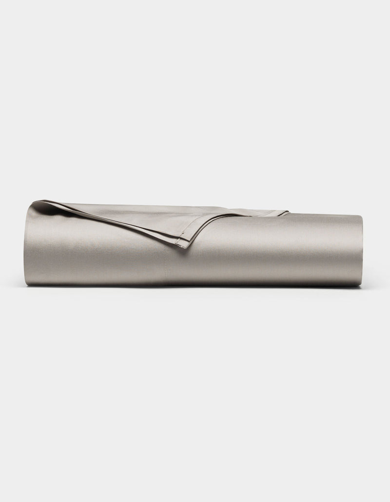 The Cozy Earth Bamboo Flat Sheet, in light gray, is neatly rolled and displayed on a plain white background.