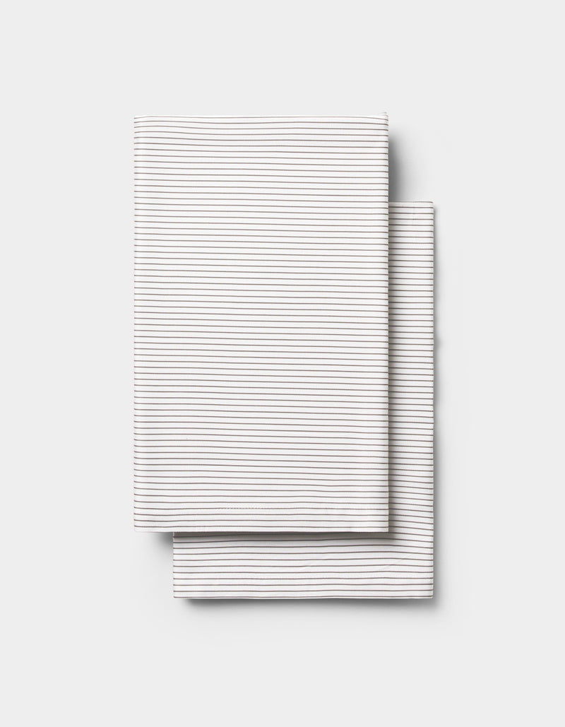 Two neatly folded Cozy Earth Bamboo Pillowcases, white with thin horizontal gray stripes, stacked on a plain light gray background.