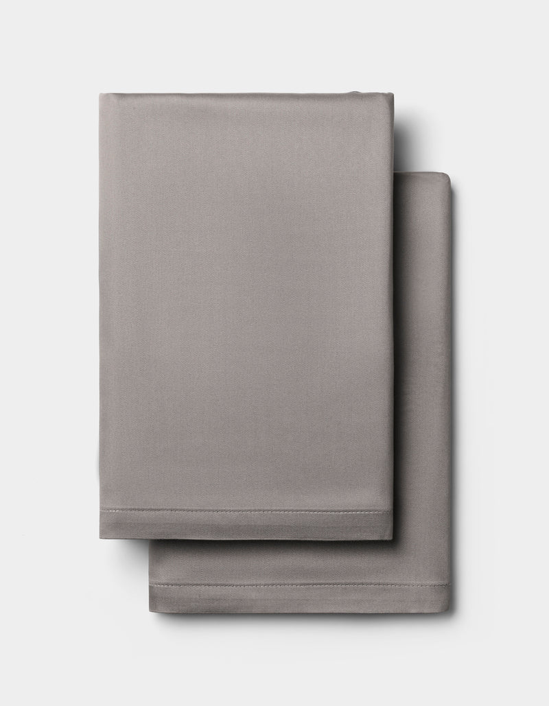 Two light gray Cozy Earth Bamboo Pillowcases, neatly folded and stacked against a plain white background.
