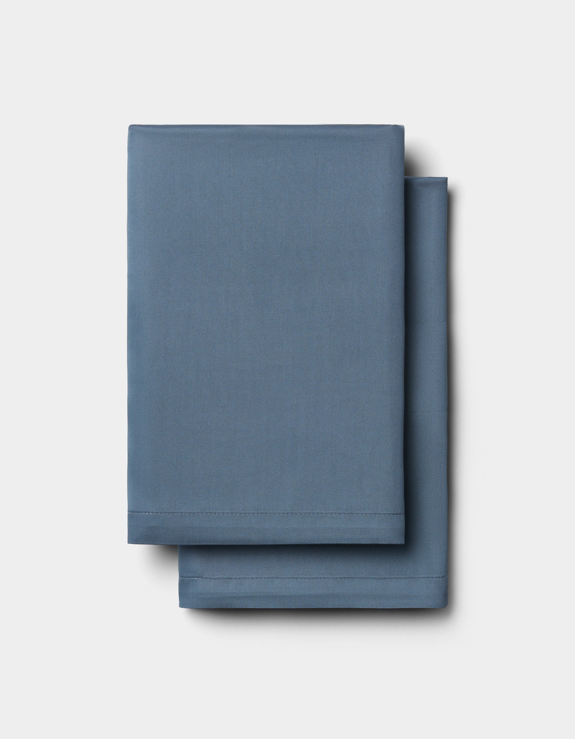 Two neatly folded Cozy Earth Bamboo Pillowcases stacked on top of each other against a plain white background.|Color:Pacific Blue