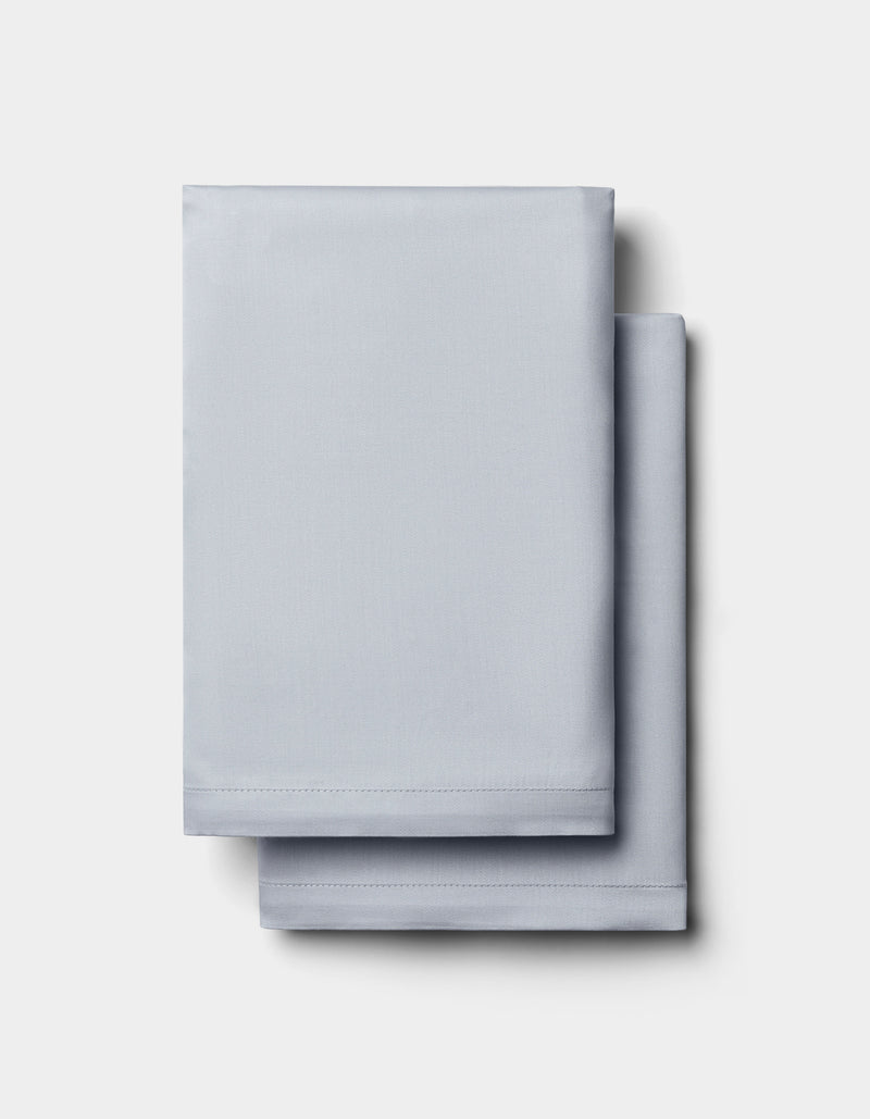Two neatly folded Cozy Earth Bamboo Pillowcases in light gray are stacked on a plain white background.