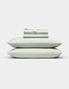 The Cozy Earth Bamboo Sheet Set, in light gray, features neatly folded bed sheets with two matching pillowcases stacked on top, displayed against a plain white background.|Color:Laurel