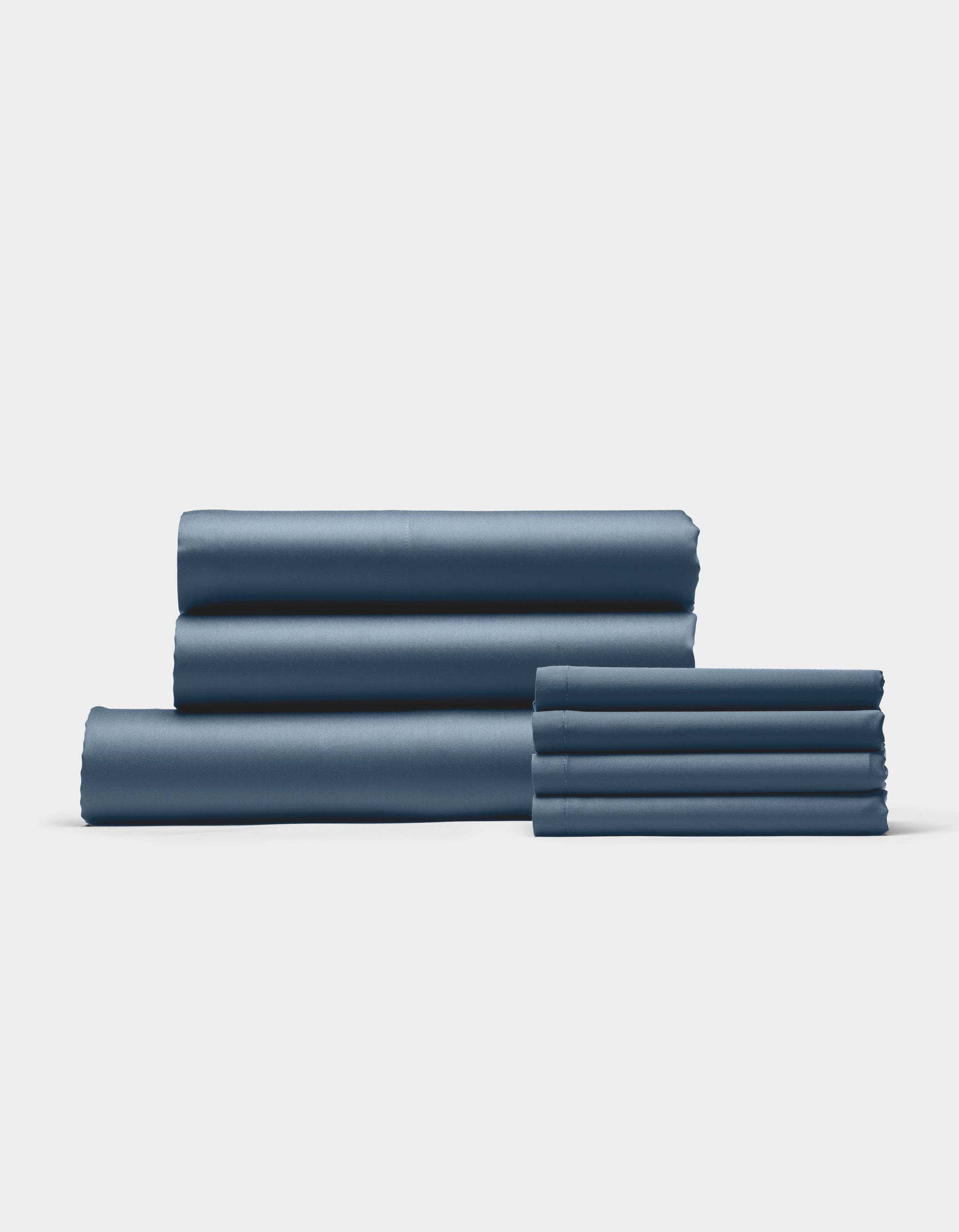 The Cozy Earth Bamboo Bedding Core Bundle features neatly folded blue bed sheets and pillowcases arranged in two stacks on a plain white background.