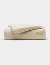 The Cozy Earth Cuddle Blanket, a plush cream-colored faux fur throw, is neatly folded and displayed against a plain white background.|Color:Creme