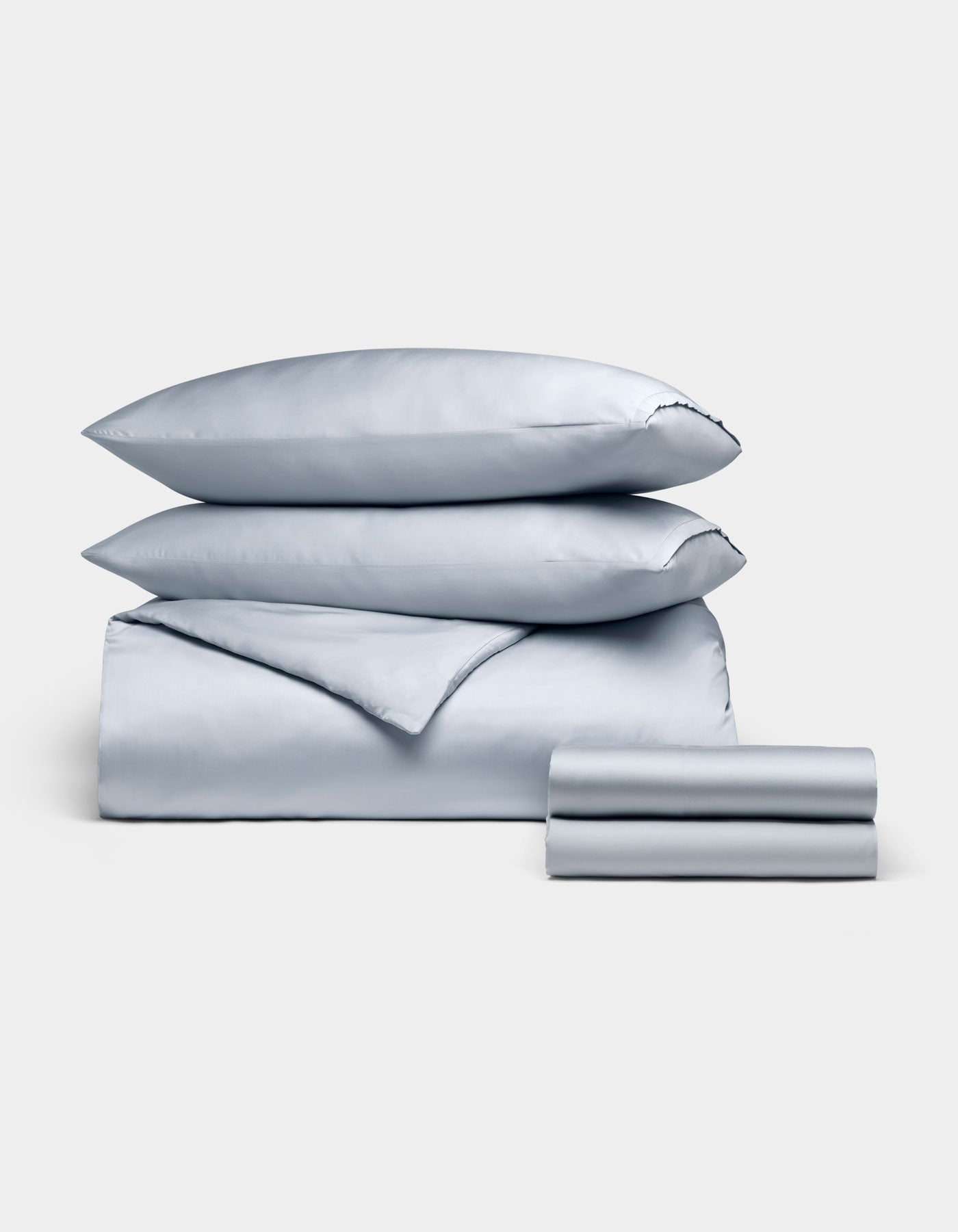 The Cozy Earth Bamboo Bedding Deluxe Bundle features a neatly folded light blue set with two pillowcases, a flat sheet, fitted sheet, and comforter, all arranged on a plain light background.|Color:Shore