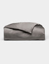 A neatly folded, shiny gray Bamboo Duvet Cover by Cozy Earth is displayed on a plain white background.|Color:Charcoal