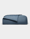 The Cozy Earth Bamboo Duvet Cover, in dark blue and rectangular shape, features plush fabric with a partially folded comforter, displayed against a plain light gray background.|Color:Pacific Blue