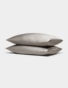 Two Cozy Earth Bamboo Pillowcases in light gray satin are stacked against a plain white background.|Color:Dove Grey