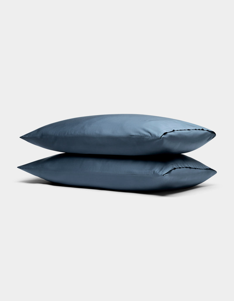 Two Cozy Earth Bamboo Pillowcases in blue are stacked against a plain, light gray background.