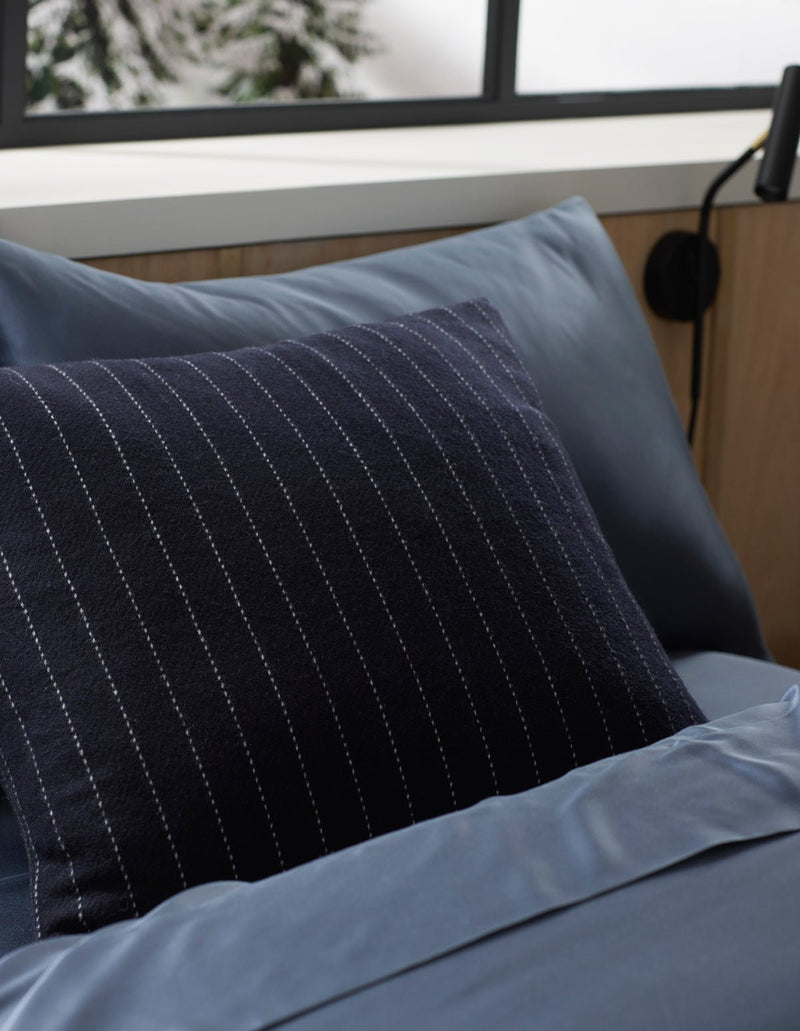 Blue bedding with a Cozy Earth Florence pillow on a bed in a bedroom setting.