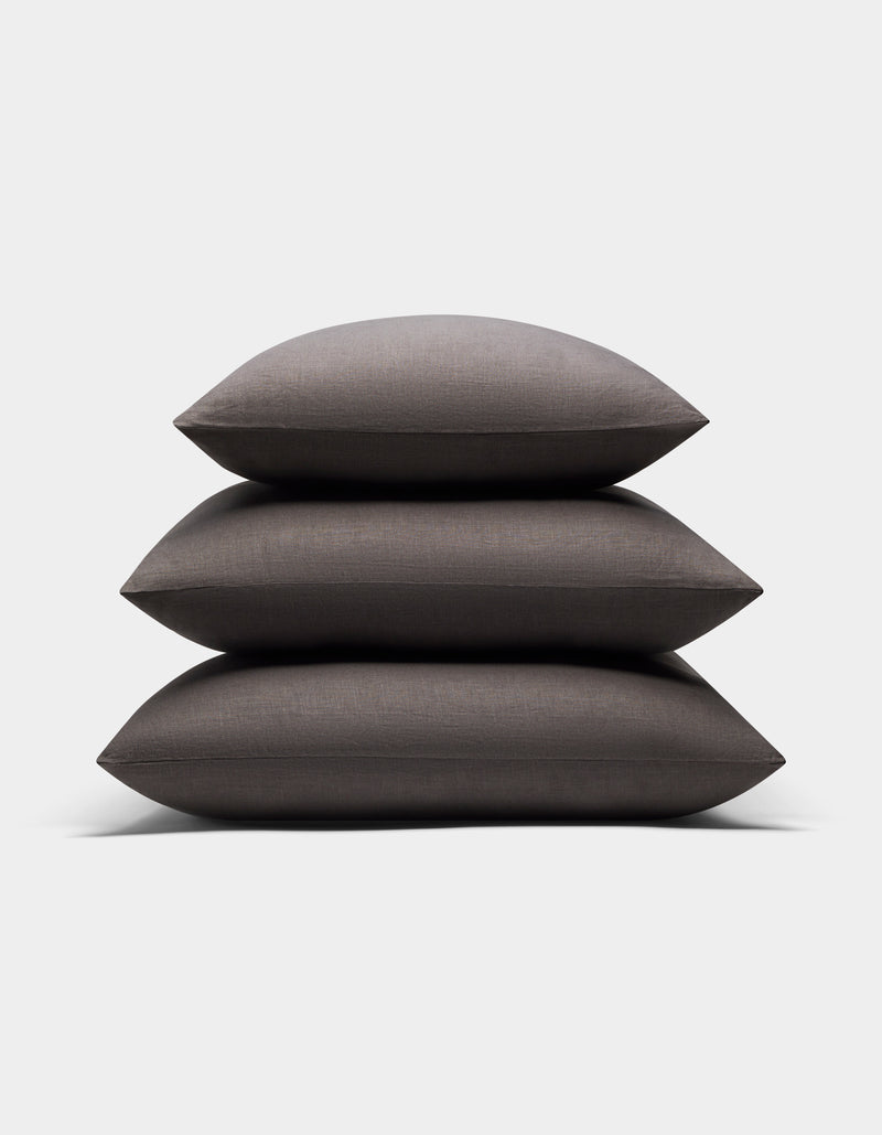Three Cozy Earth Linen Throw Pillows in dark gray are neatly stacked together against a plain white background.