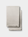 Two neatly folded Cozy Earth Silk Pillowcases in light beige are stacked together against a plain white background.|Color:Dove Grey
