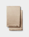 Two neatly folded Cozy Earth Silk Pillowcases in a champagne hue are stacked on a plain white background.|Color:Walnut