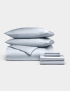 The Cozy Earth Bamboo Bedding Ultimate Bundle is showcased neatly with two stacked pillows, a duvet cover, a folded sheet, and two pillowcases in light gray, all set against a plain white background.|Color:Shore