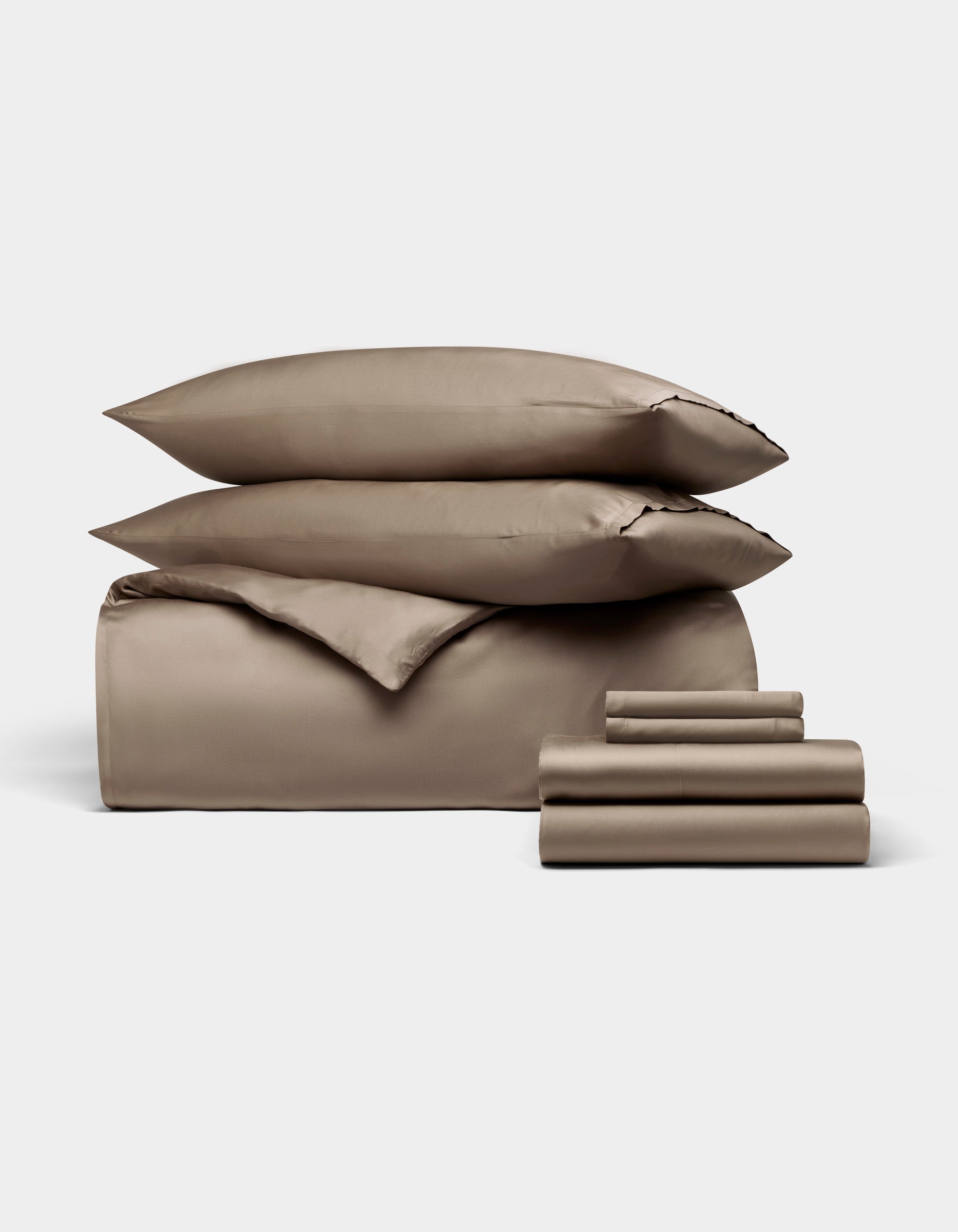 The Bamboo Bedding Ultimate Bundle by Cozy Earth features taupe-colored sheets, a fitted sheet, flat sheet, pillowcases, and two stacked pillows, all neatly arranged against a plain white background.|Color:Walnut