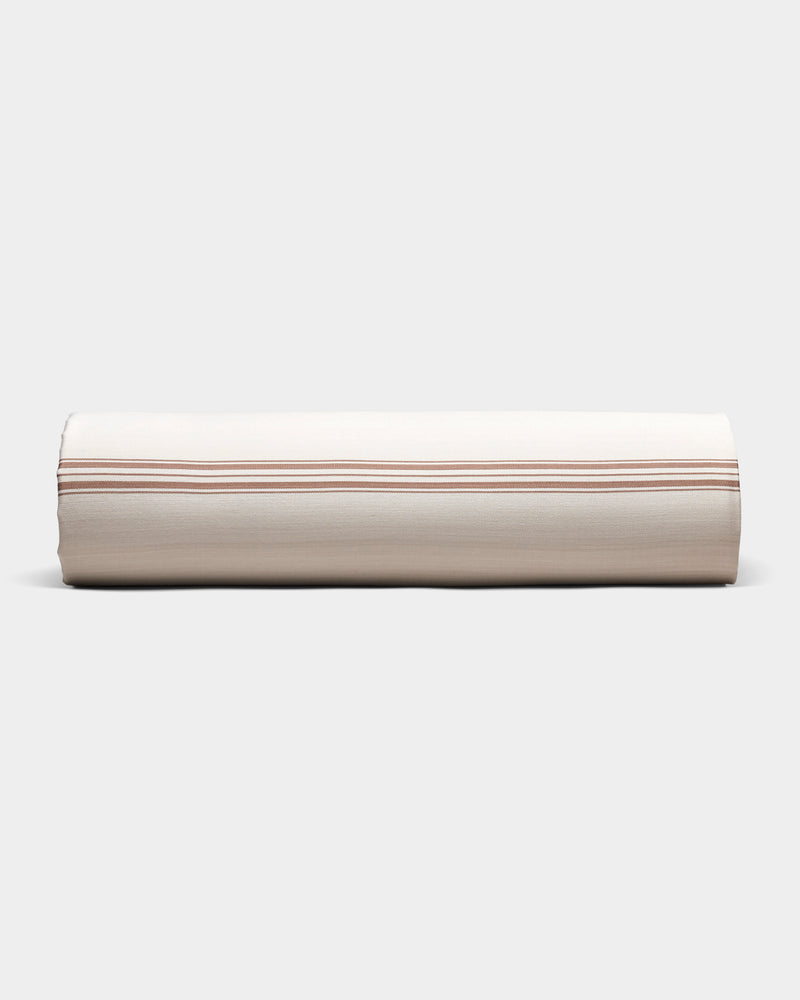 The Cozy Earth Bamboo Sheet Set is shown neatly rolled in beige fabric with thin, evenly spaced brown stripes, on a plain light gray background.