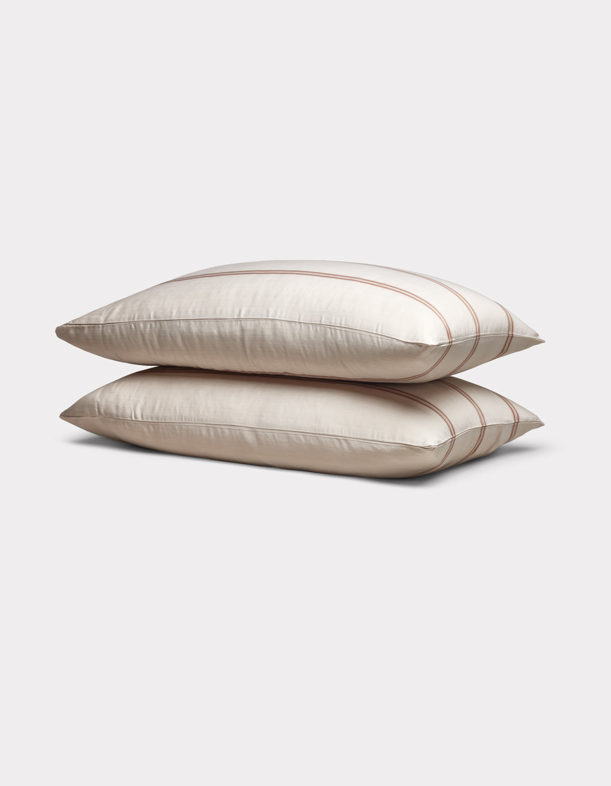 Two Cozy Earth Bamboo Pillowcases in cream with subtle brown stripes are stacked neatly on a plain light gray background.|Color:Baja Stripe in Maple