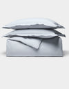 The Cozy Earth Soft-Wash Cotton Duvet Bundle features a neatly folded light gray set, including two stacked pillows and a duvet, displayed on a plain white background.|Color:Shore