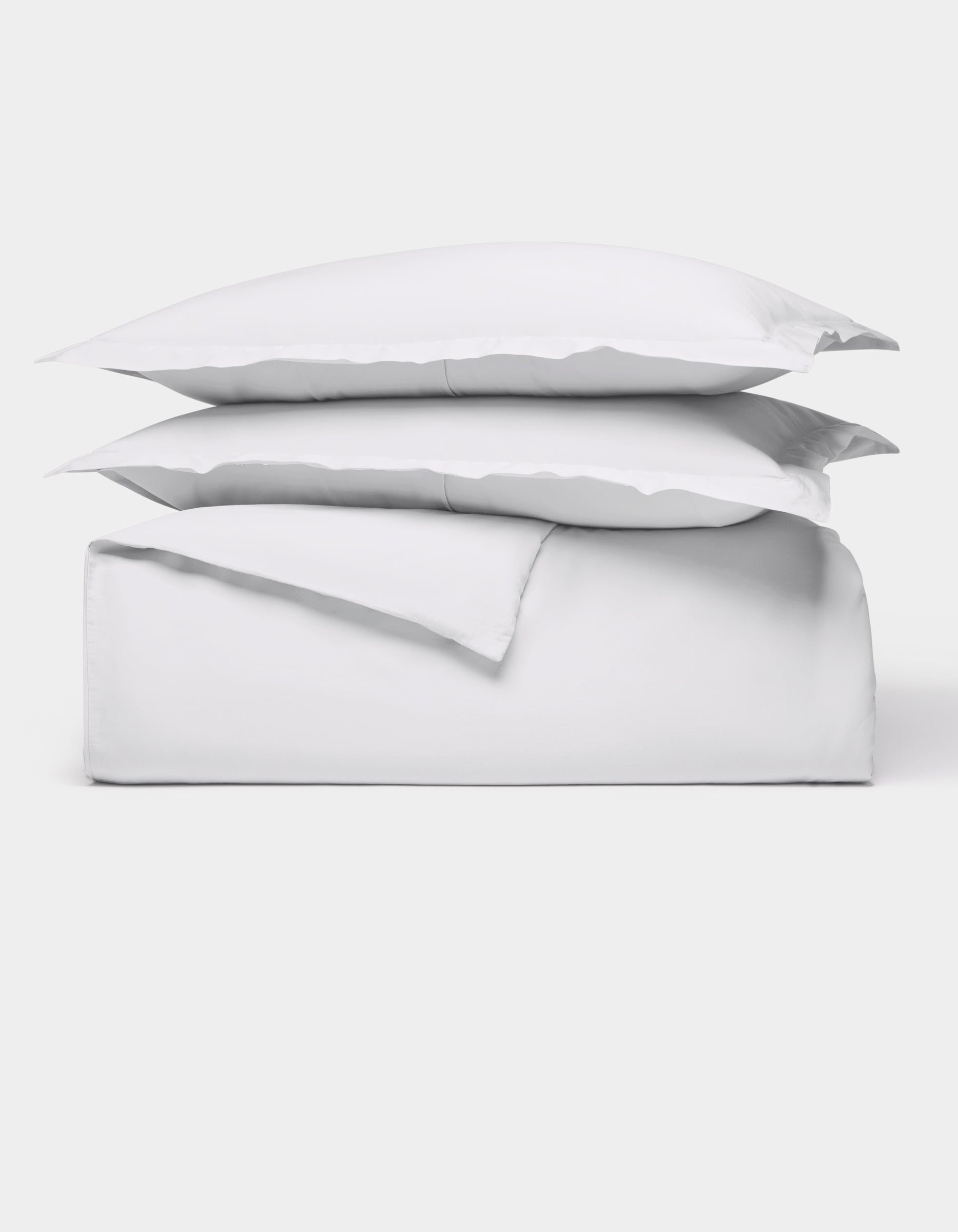 The Cozy Earth Soft-Wash Cotton Duvet Bundle features a neatly folded white sheet set with two stacked pillows, all displayed against a plain white background.|Color:White
