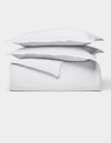 The Cozy Earth Soft-Wash Cotton Duvet Bundle features a neatly folded white sheet set with two stacked pillows, all displayed against a plain white background.|Color:White